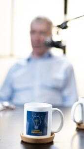 Sound Leadership podcast mug on a table with blurred host and microphone in the background