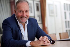 Stephen Bath smiling in a smart blue suit at a table